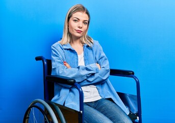 Beautiful caucasian woman sitting on wheelchair skeptic and nervous, disapproving expression on face with crossed arms. negative person.