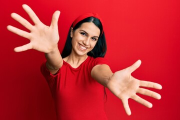 Young hispanic woman wearing casual clothes looking at the camera smiling with open arms for hug. cheerful expression embracing happiness.