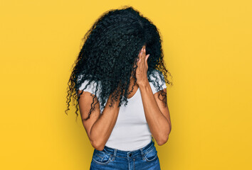 Middle age african american woman wearing casual white t shirt with sad expression covering face with hands while crying. depression concept.