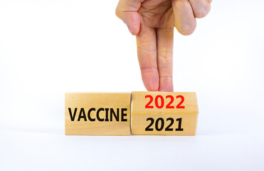 Symbol of covid-19 vaccine in 2022. Doctor turns a wooden cube and changes words 'vaccine 2021' to 'vaccine 2022'. Beautiful white background, copy space. Medical, covid-19 vaccine in 2022 concept.