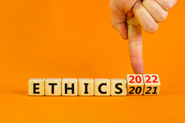 2022 ethics and new year symbol. Businessman turns wooden cubes and changes words 'ethics 2021' to 'ethics 2022'. Beautiful orange background, copy space. Business, 2022 ethics and new year concept.
