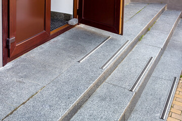 granite threshold at the open brown entrance door with rubber non-slip strips on steps of building...