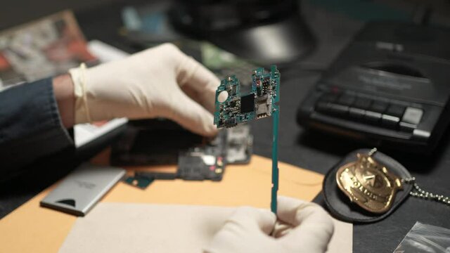 Police Detective Looking at Hacked Electronic Device