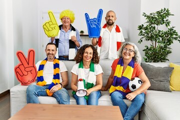 Group of senior people supporting soccer team at home looking positive and happy standing and smiling with a confident smile showing teeth