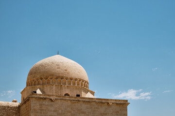 Fototapeta na wymiar Dome of madrasah opposite summer blue sky. Kasimiye Medrese, Mardin, Turkey
