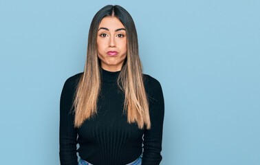 Young hispanic woman wearing casual clothes puffing cheeks with funny face. mouth inflated with...