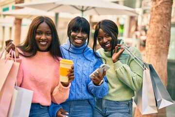 Three african american friends going shopping. Using smartphone and drinking coffee at the city.