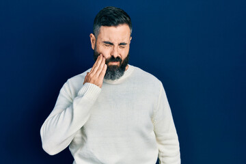Young hispanic man wearing casual clothes touching mouth with hand with painful expression because of toothache or dental illness on teeth. dentist