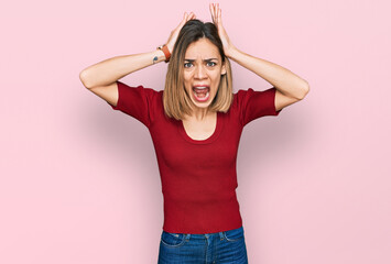 Young blonde girl wearing casual clothes crazy and scared with hands on head, afraid and surprised of shock with open mouth