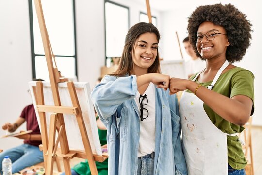 Group of young draw students drawing at art studio. Two woman smiling happy bumb fists.