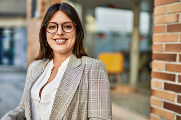 Young hispanic businesswoman smiling happy standing at the city.