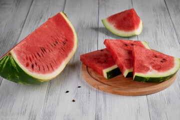 Close-up of sliced pieces of ripe red watermelon on a light wooden surface. Healthy food concept, summer food. Selective focus.