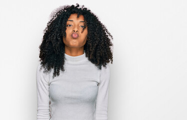 Young african american girl wearing casual clothes puffing cheeks with funny face. mouth inflated with air, crazy expression.