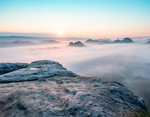 Mountain top rock, sleepy misty landscape bellow under morning mist.