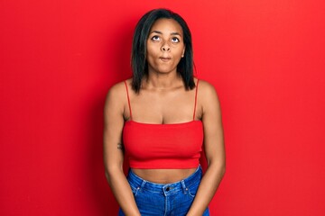 Young african american girl wearing casual style with sleeveless shirt making fish face with lips, crazy and comical gesture. funny expression.