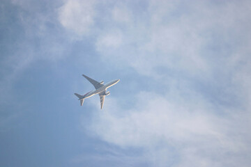 Fototapeta na wymiar Airplane flying in the blue sky with white clouds. Passenger plane at flight, travel concept