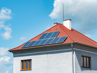 Electric solar panels on the tiled roof of family house. The insulated facade