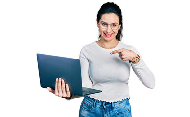 Young hispanic woman working using computer laptop smiling happy pointing with hand and finger