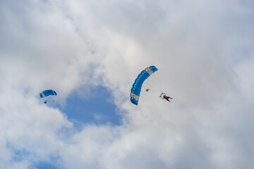 Skydiving as an exciting but extreme sport. People descend on blue parachutes