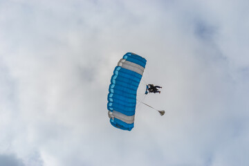 Skydiving as an exciting but extreme sport. People descend on blue parachutes