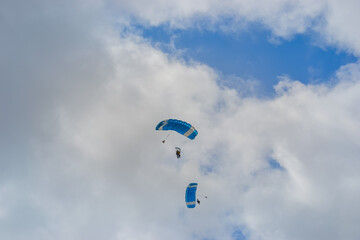 Skydiving as an exciting but extreme sport. People descend on blue parachutes