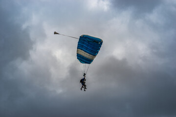 Skydiving as an exciting but extreme sport. People descend on blue parachutes