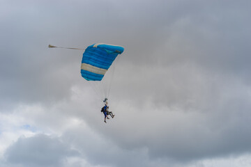Skydiving as an exciting but extreme sport. People descend on blue parachutes