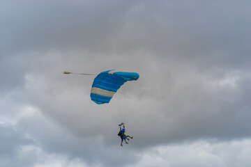 Skydiving as an exciting but extreme sport. People descend on blue parachutes