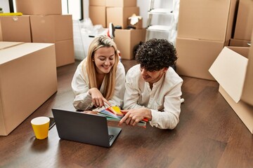 Young beautiul couple using laptop choosing painting color at new home.