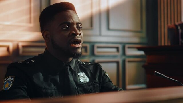 Court of Law and Justice Trial Stand: Portrait of Black Policeman Witness Giving Testimony to Judge, Jury. African American Officer Providing Evidence. Law Enforcement Agent in Courthouse.