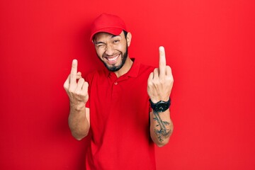 Hispanic man with beard wearing delivery uniform and cap showing middle finger doing fuck you bad...