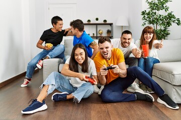 Fototapeta premium Group of young friends smiling happy playing video game at home.