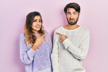 Young hispanic couple wearing casual clothes pointing aside worried and nervous with both hands, concerned and surprised expression