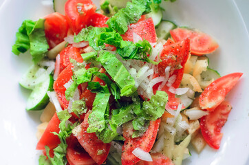 healthy salad with fresh ripe summer vegetables , tomato, cucumber , spices on a light background.