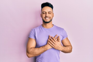 Young arab man wearing casual clothes smiling with hands on chest with closed eyes and grateful gesture on face. health concept.