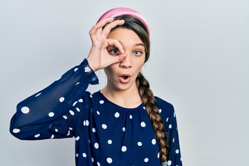 Young brunette girl wearing elegant look doing ok gesture shocked with surprised face, eye looking through fingers. unbelieving expression.