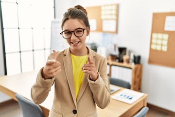 Young brunette teenager wearing business style at office pointing fingers to camera with happy and funny face. good energy and vibes.