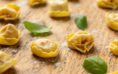 Mini raw Ravioli with flour and basil on wooden board
