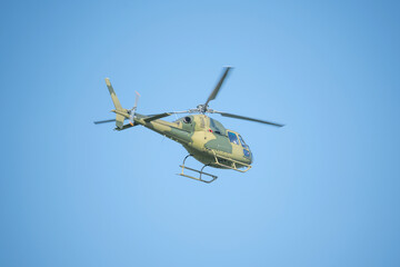 Flight of the military helicopter in the sky at sunny day.