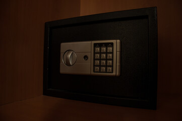 Small modern safe on shelf in dark. Small safe box close up in low key light