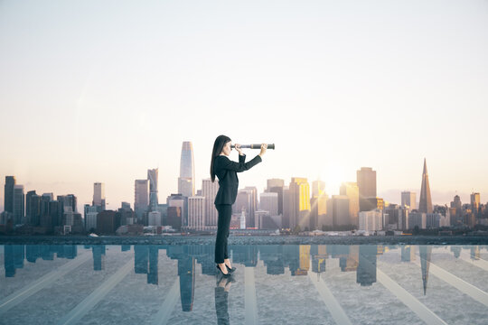 Business woman on glass balcony looking into the distance with telescope at city with mock up place. Success and future concept.