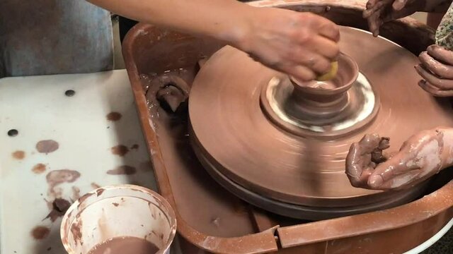 Hands of mother and child shaping clay on a ceramics pottery wheel