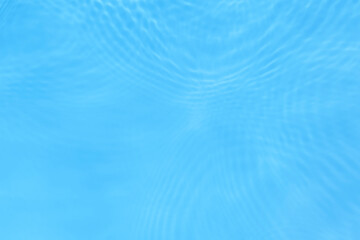 The surface of light on the blue transparent swimming pool water. Trendy abstract wavy background. Water waves in sunlight banner.