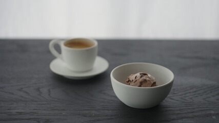 Chocolate ice cream in white bowl next to cup of espresso