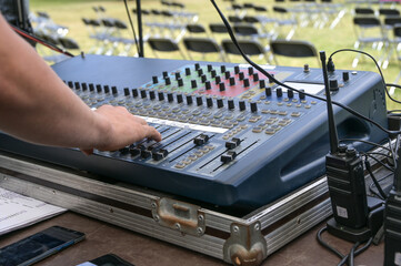 Hand of the sound mixer pushes buttons on a mixing console during soundcheck for an open air...