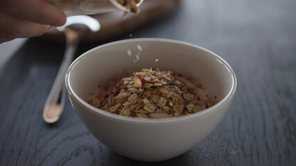 Pour granola over yogurt in white bowl