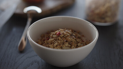 Pour granola over yogurt in white bowl