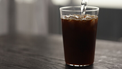 Making espresso tonic in tumbler glass, pour tonic
