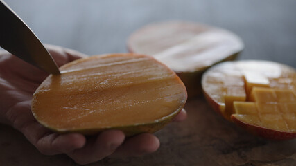 Man cut ripe big mango on olive wood board