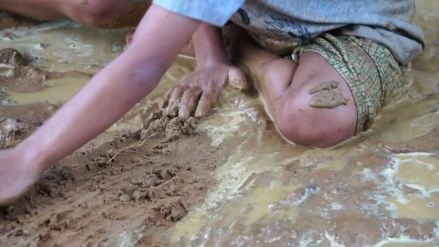 Underprivileged children happily playing in muddy water